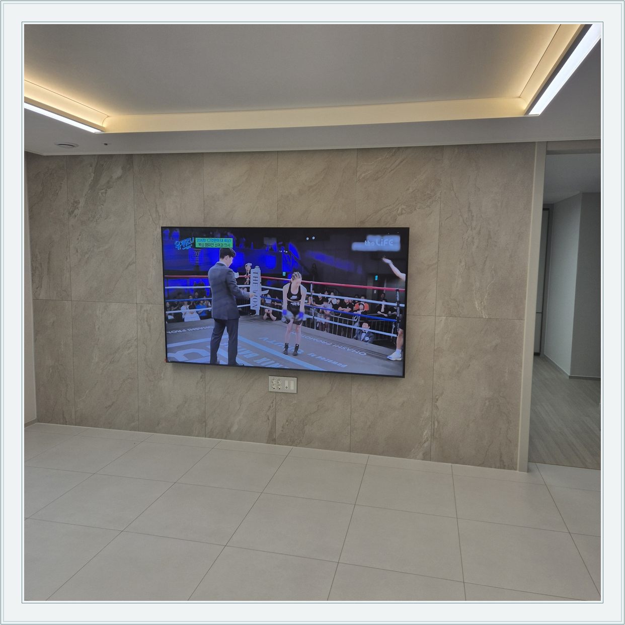 돌무늬 패널과 대형 TV, TV 아래 콘센트 패널이 드러나는 구도입니다