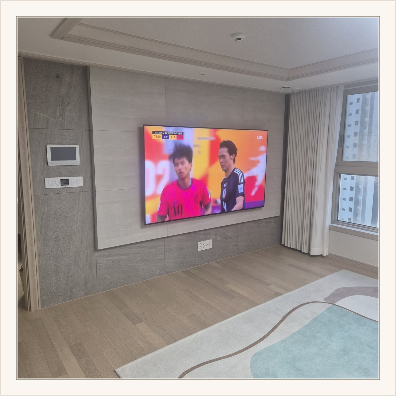 밝은 회색 아트월과 시청 공간, 밝은 몰딩과 TV 아래 전원 위치가 같이 나타납니다