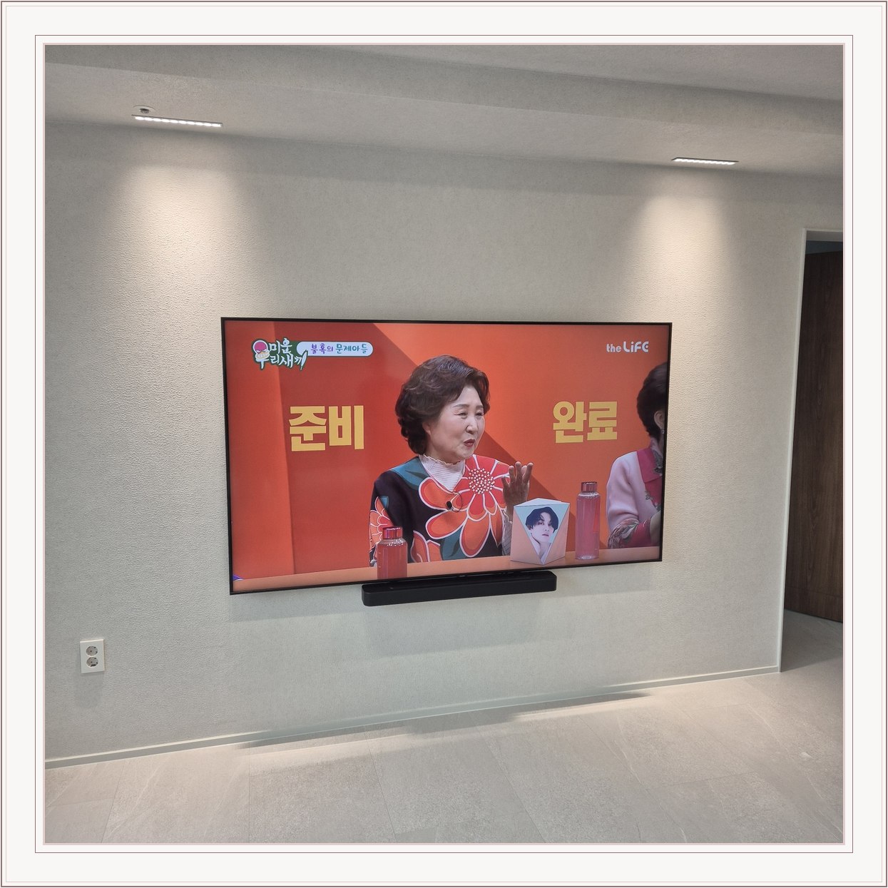 조명이 비추는 미색 벽과 사운드바, 사운드바와 벽면의 간격이 한눈에 들어옵니다